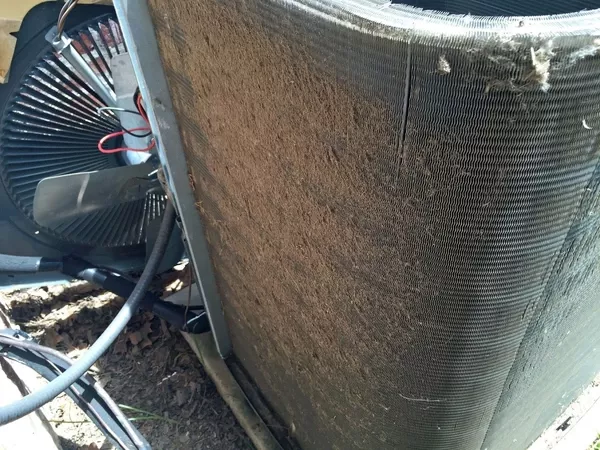 Dirty outdoor HVAC condenser coil clogged with dust and debris reducing airflow and system efficiency