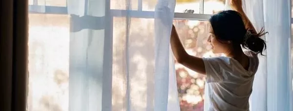 homeowner opening window to improve indoor air quality and reduce allergens in home